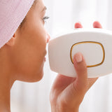 Woman using a white electronic device with a gold accent on a blurred background